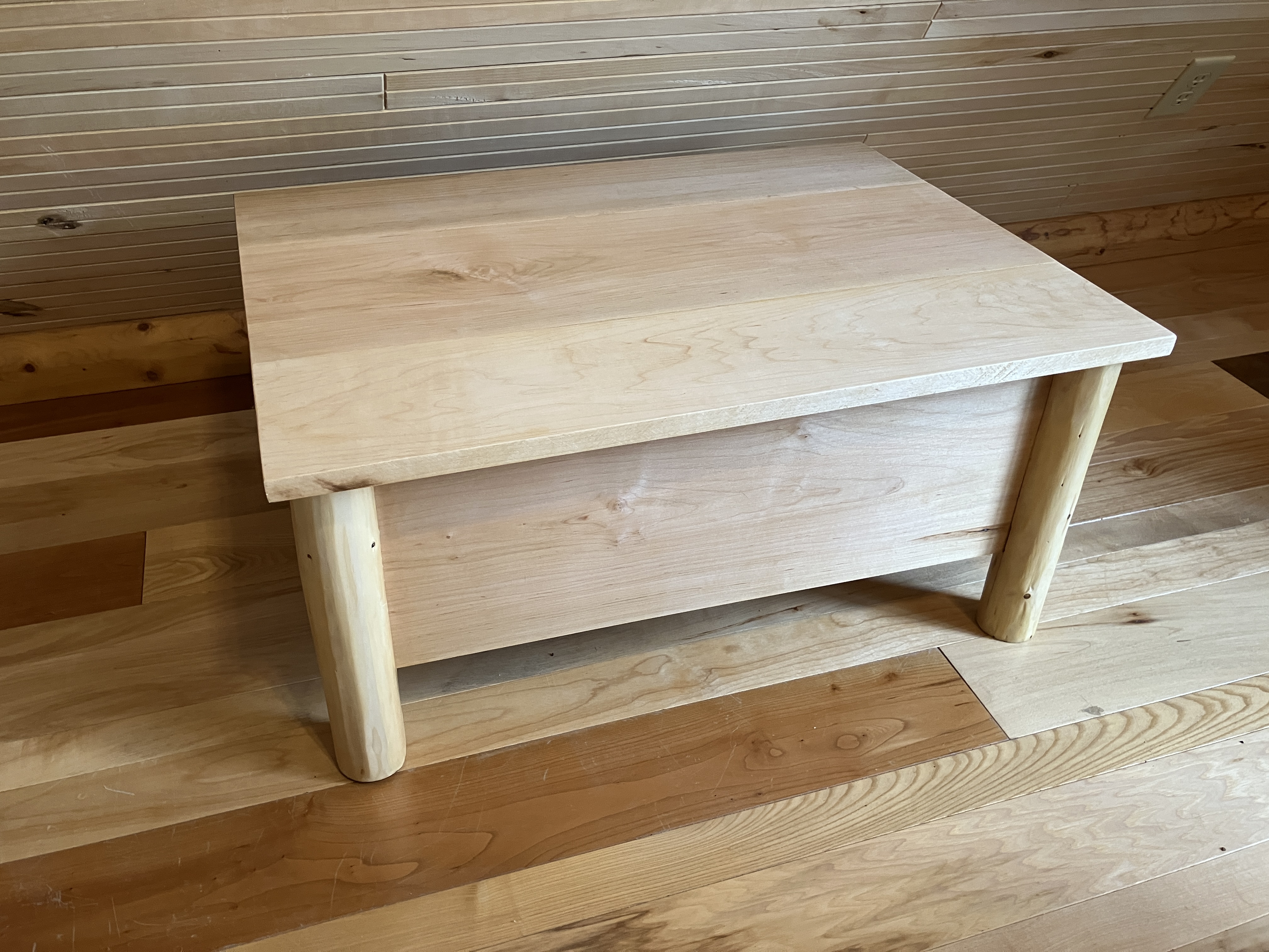 Log storage ottoman with cushioned top in cabin setting