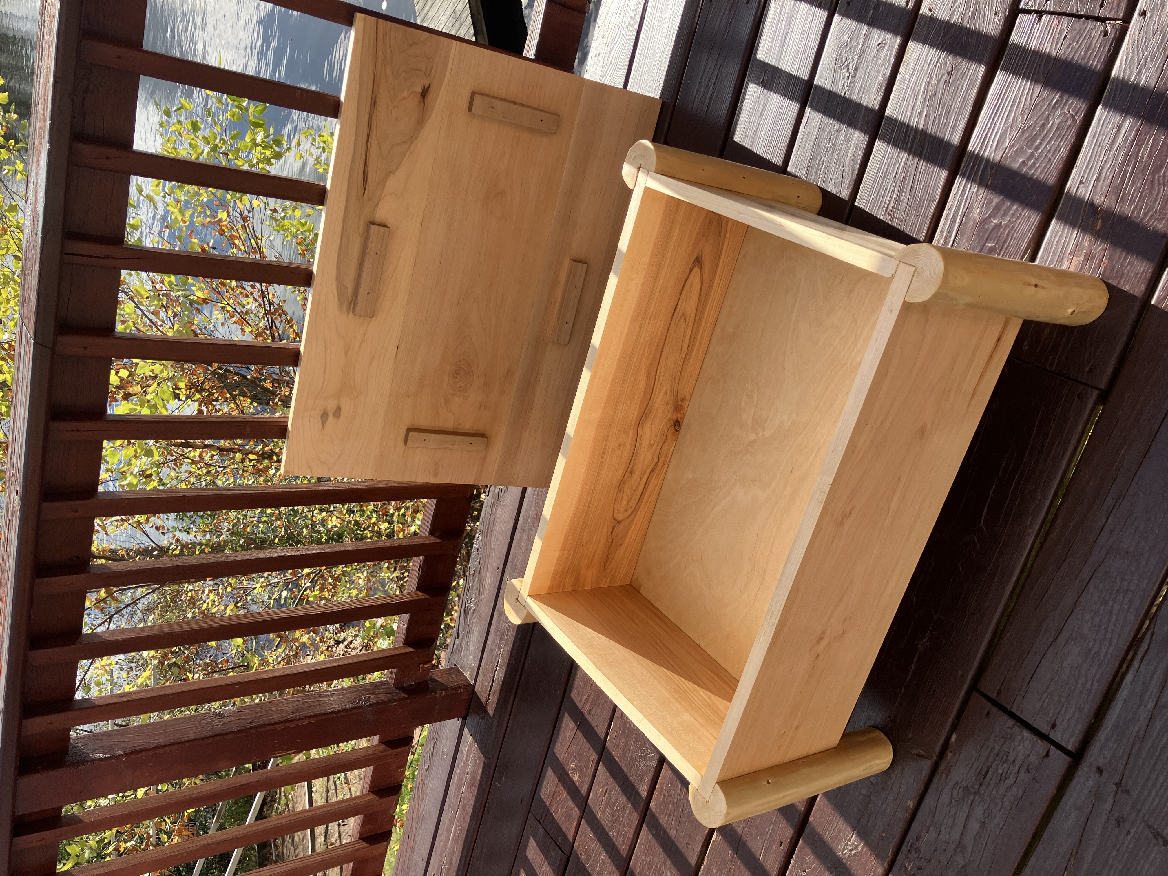 Log storage ottoman outdoors with lid open revealing depth of storage