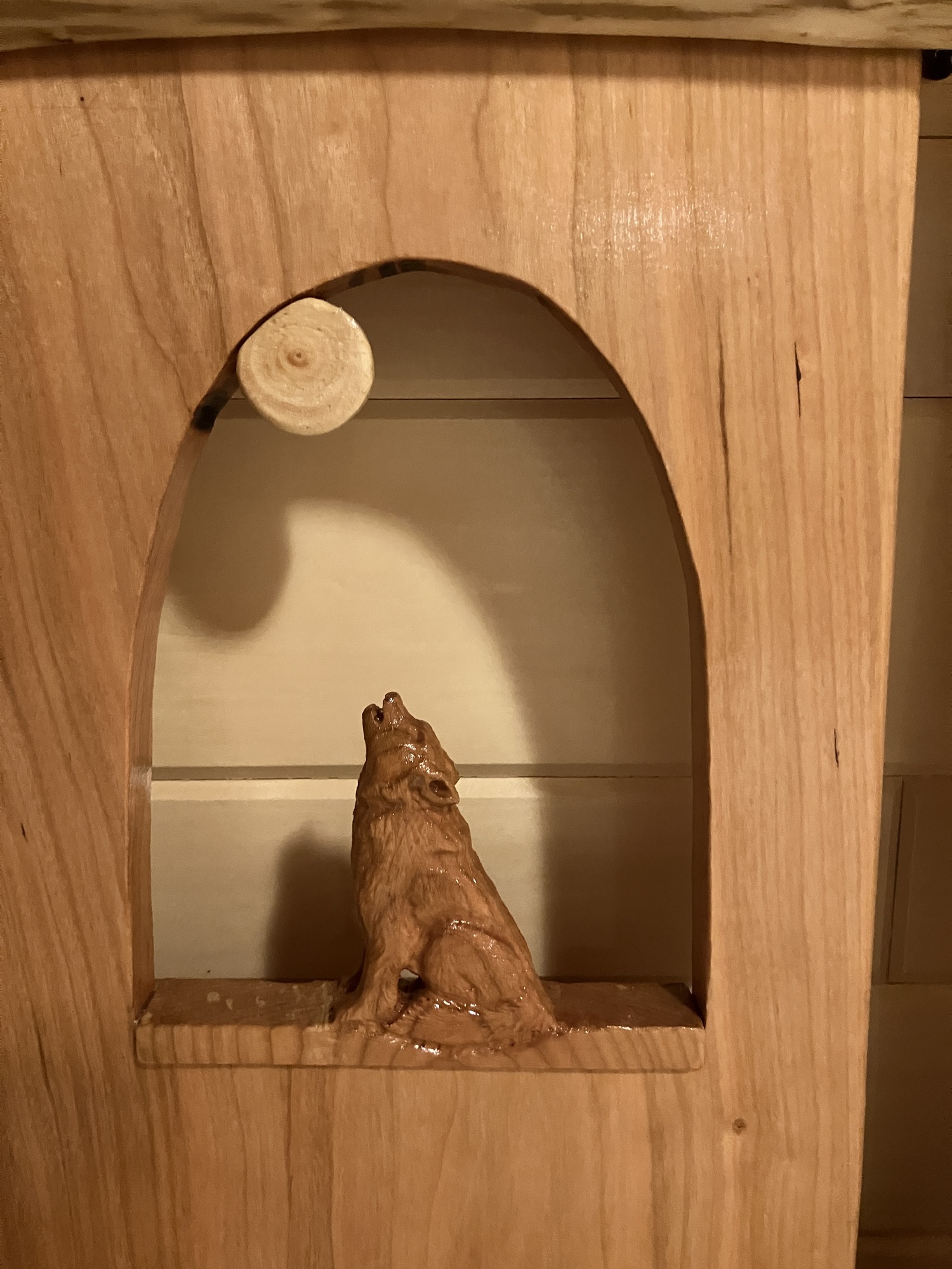 Close-up of howling wolf carving showing detailed wolf and moon design